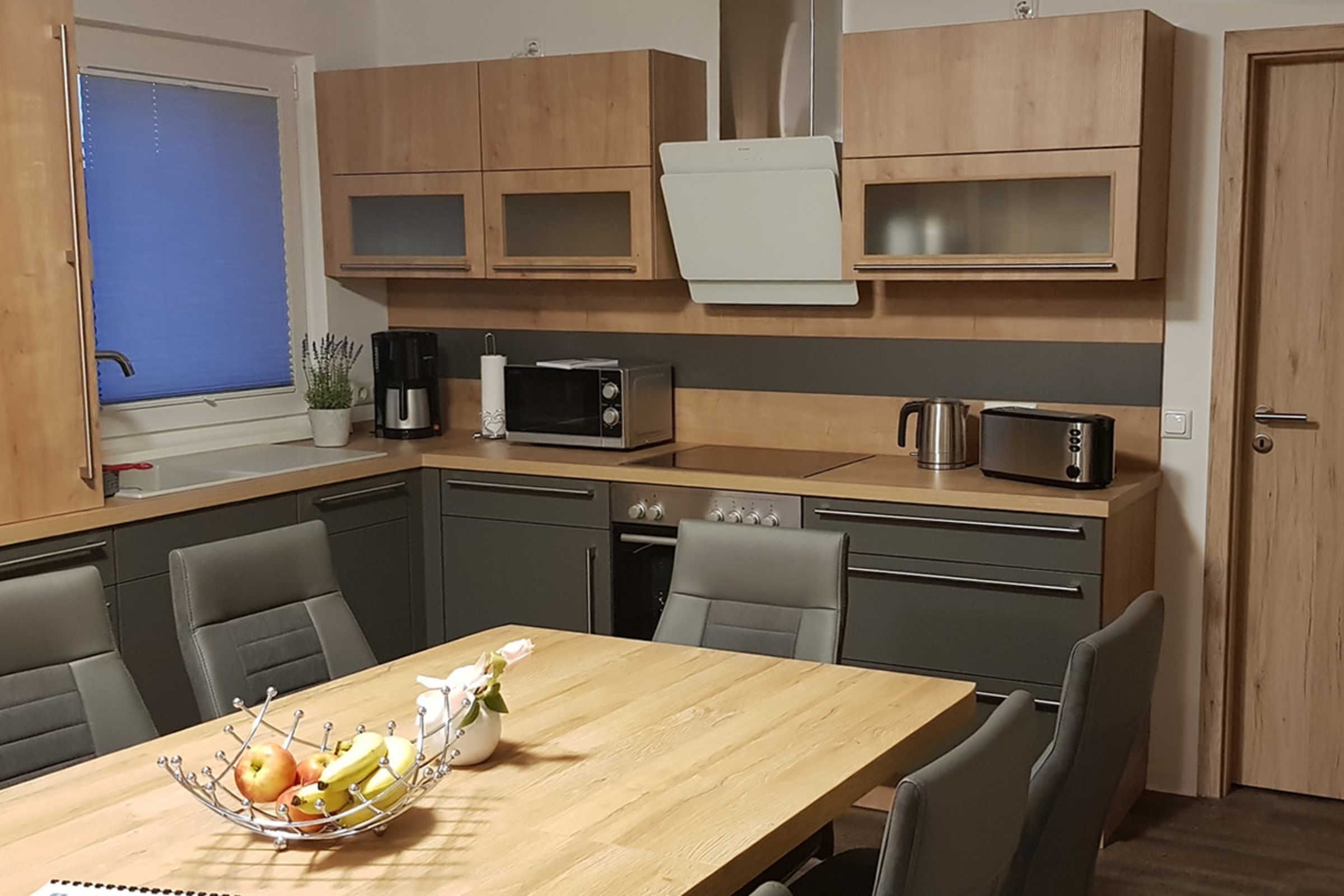 A compact kitchen with wooden cabinets, a microwave, a coffee maker, and a kettle.