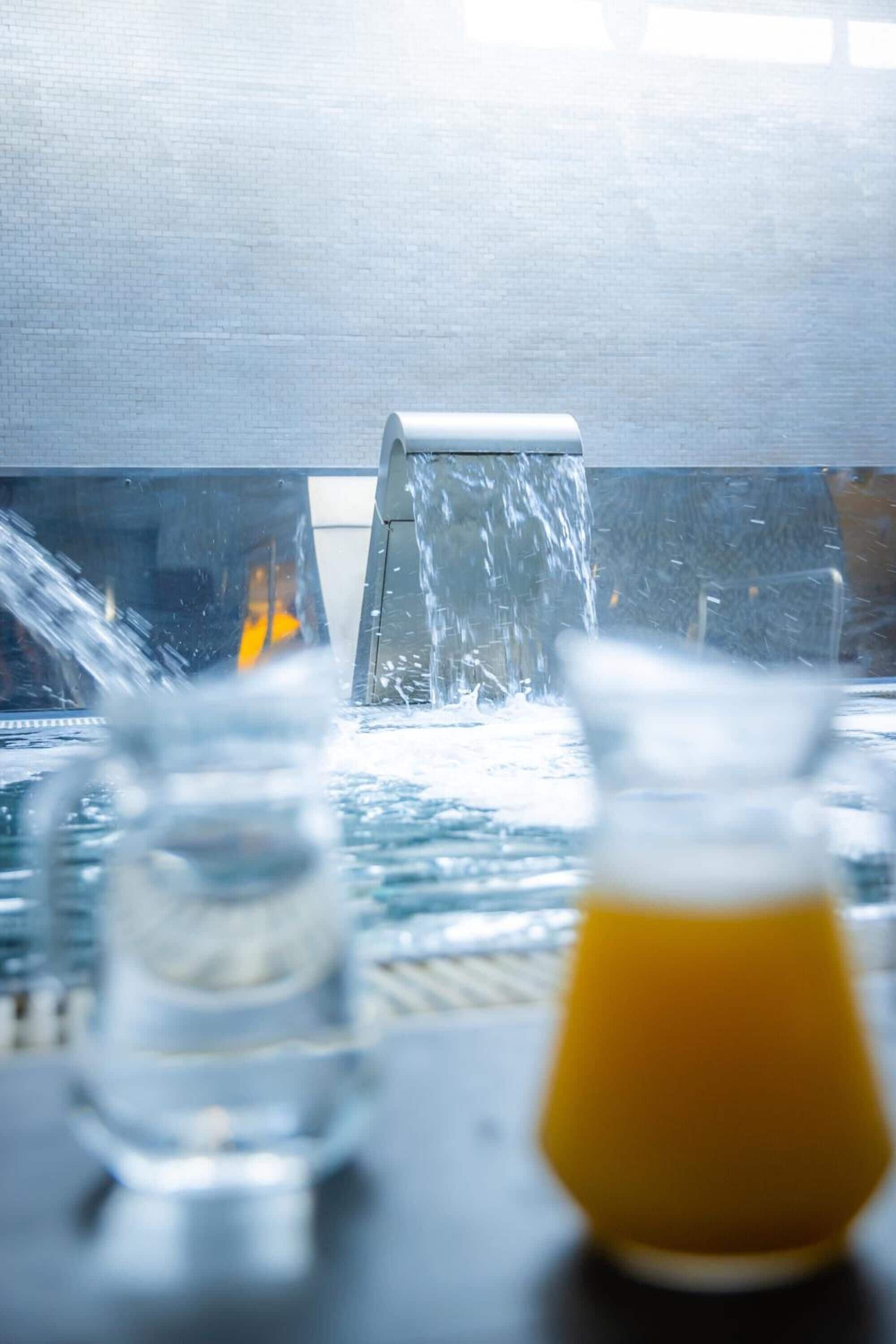 A water feature with a glass and a yellow container on a table.