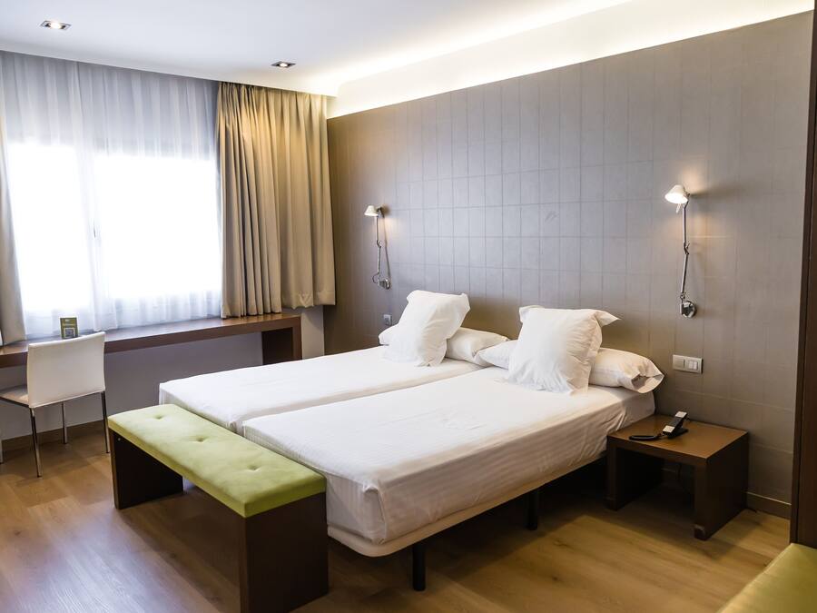 Una habitación de hotel con cama doble, un banco, un escritorio y una silla.