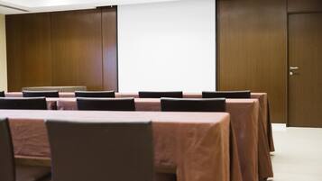 Une salle de conférence avec de longues tables et des chaises, des panneaux de bois sur les murs et une porte.