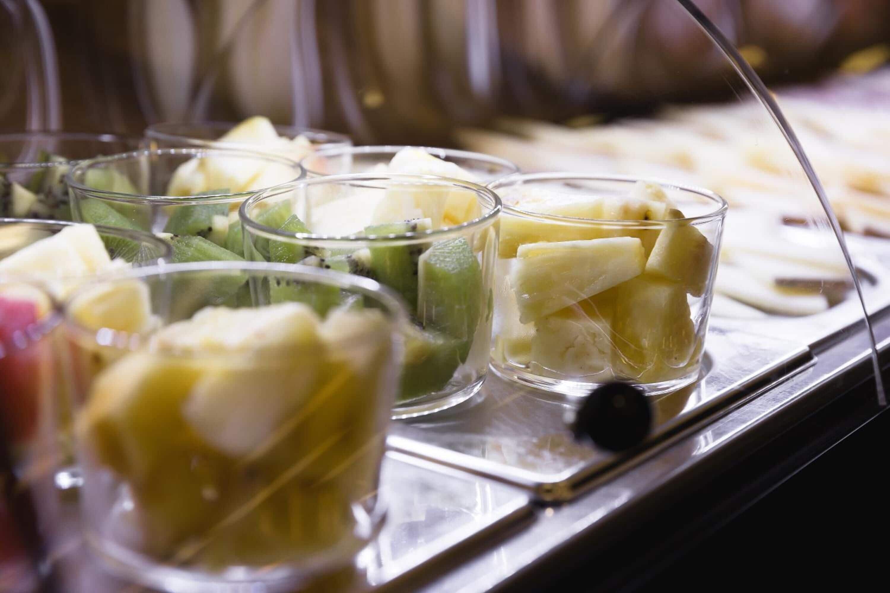 A buffet with various fruit and dessert options in clear glass bowls.