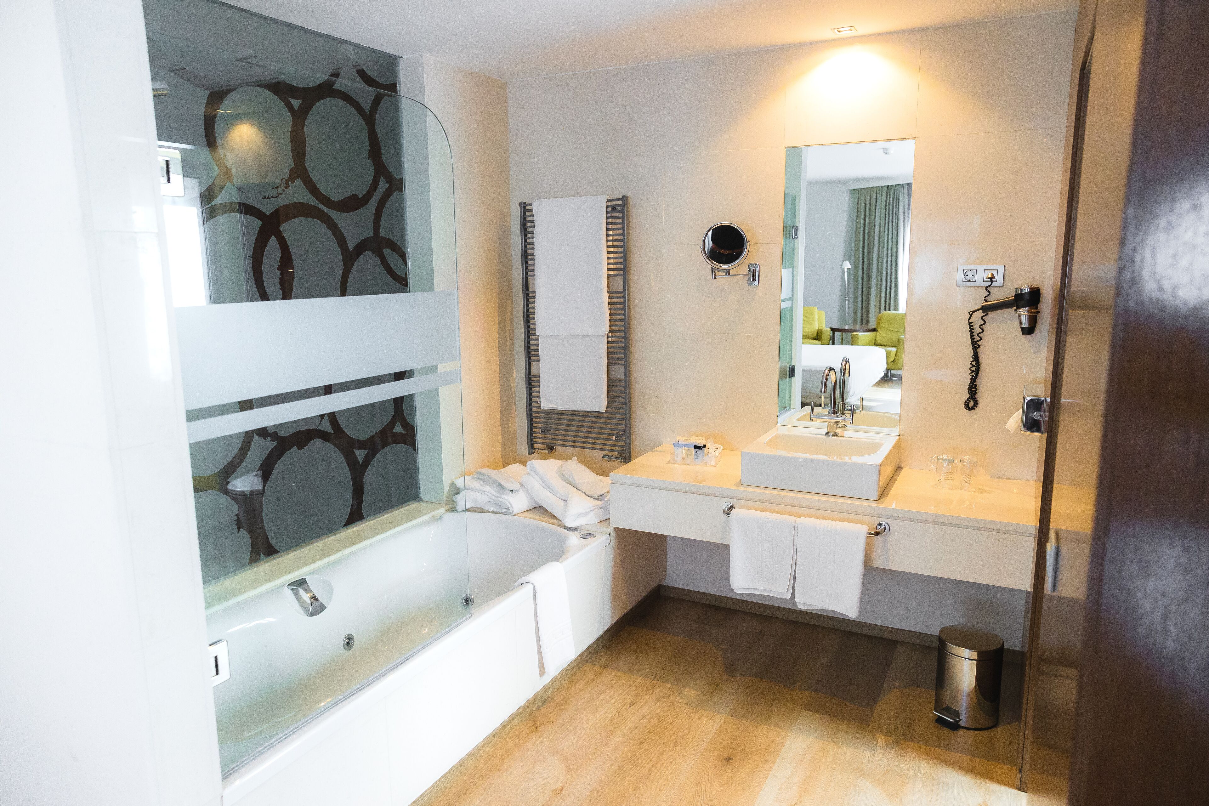 A modern bathroom with a glass-enclosed bathtub, a double sink vanity, and a large mirror.