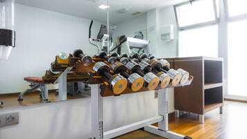 A gym with a weightlifting bench and dumbbells.