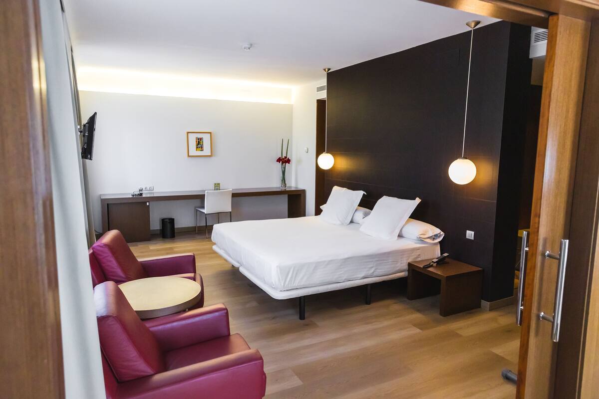 Une chambre d’hôtel moderne équipée d’un lit, d’un bureau, d’une chaise et d’une petite table.