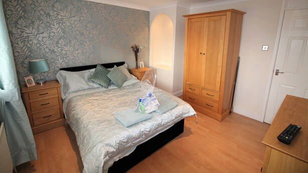 Un dormitorio con cama, armario de madera, mesitas de noche y lámpara.