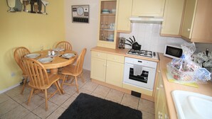 Una cocina compacta con una mesa de comedor, sillas, estufa, horno y microondas.