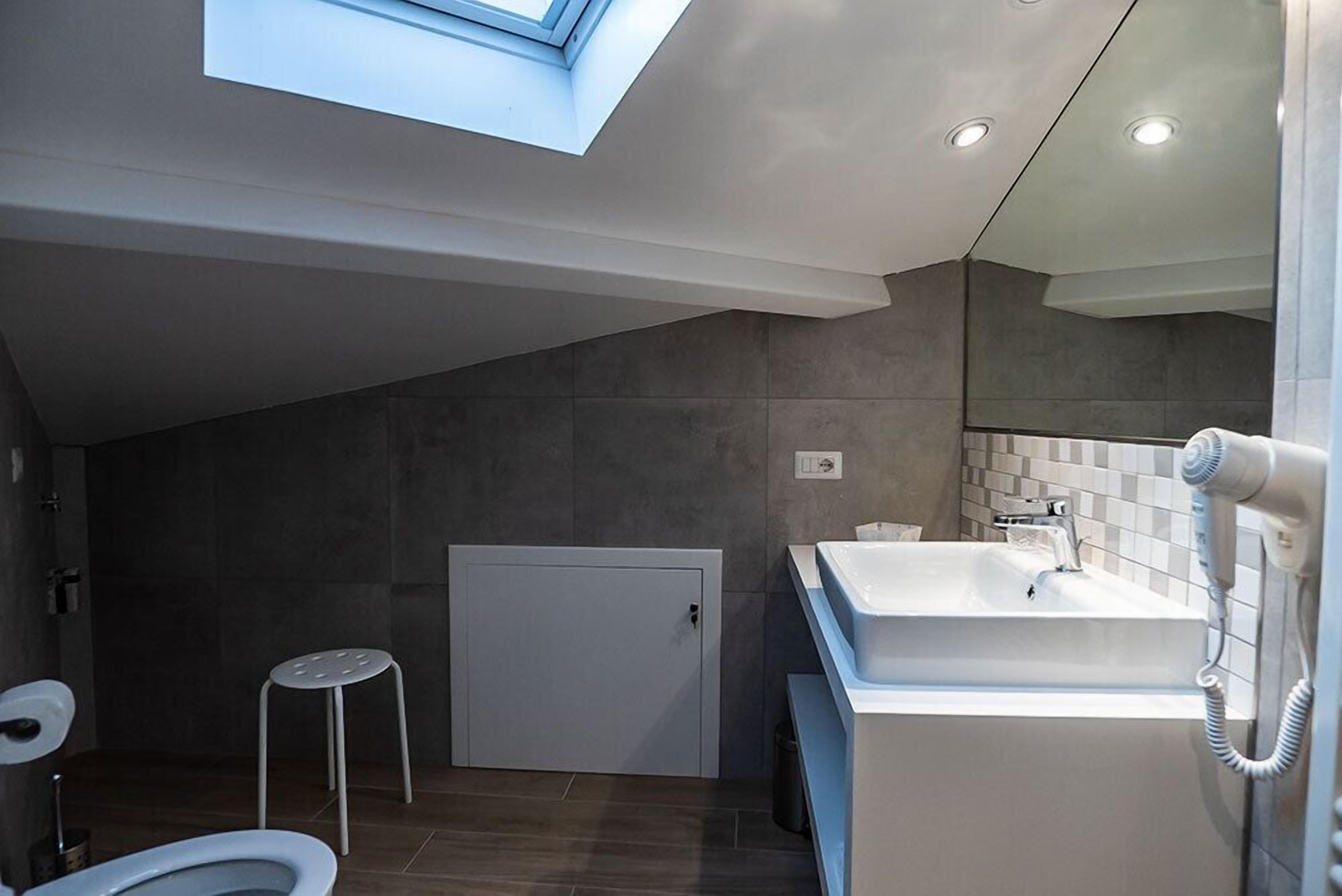 A modern bathroom with a skylight, a large sink, and a toilet.