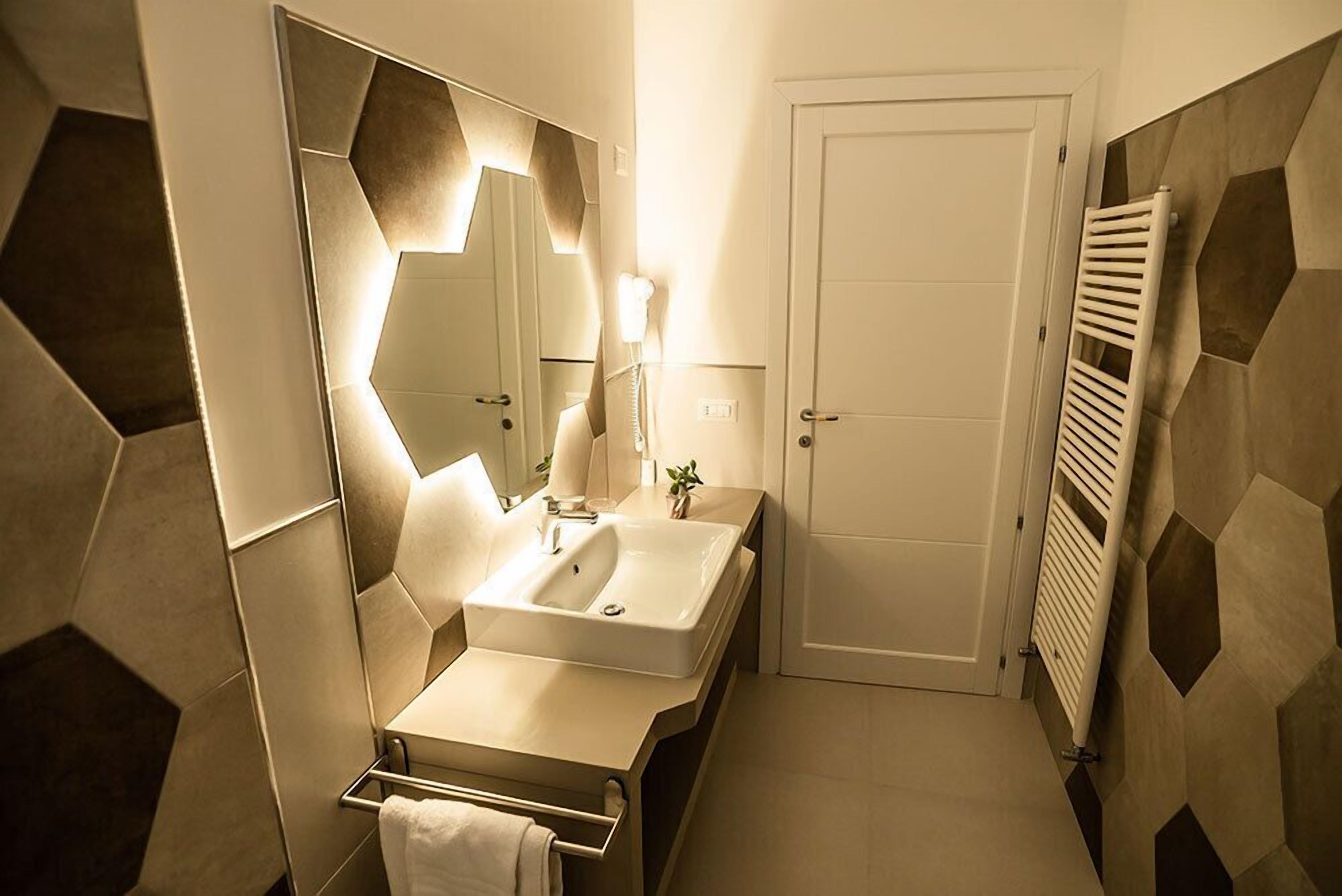 A modern bathroom with a large mirror, a sink, and a towel rack.