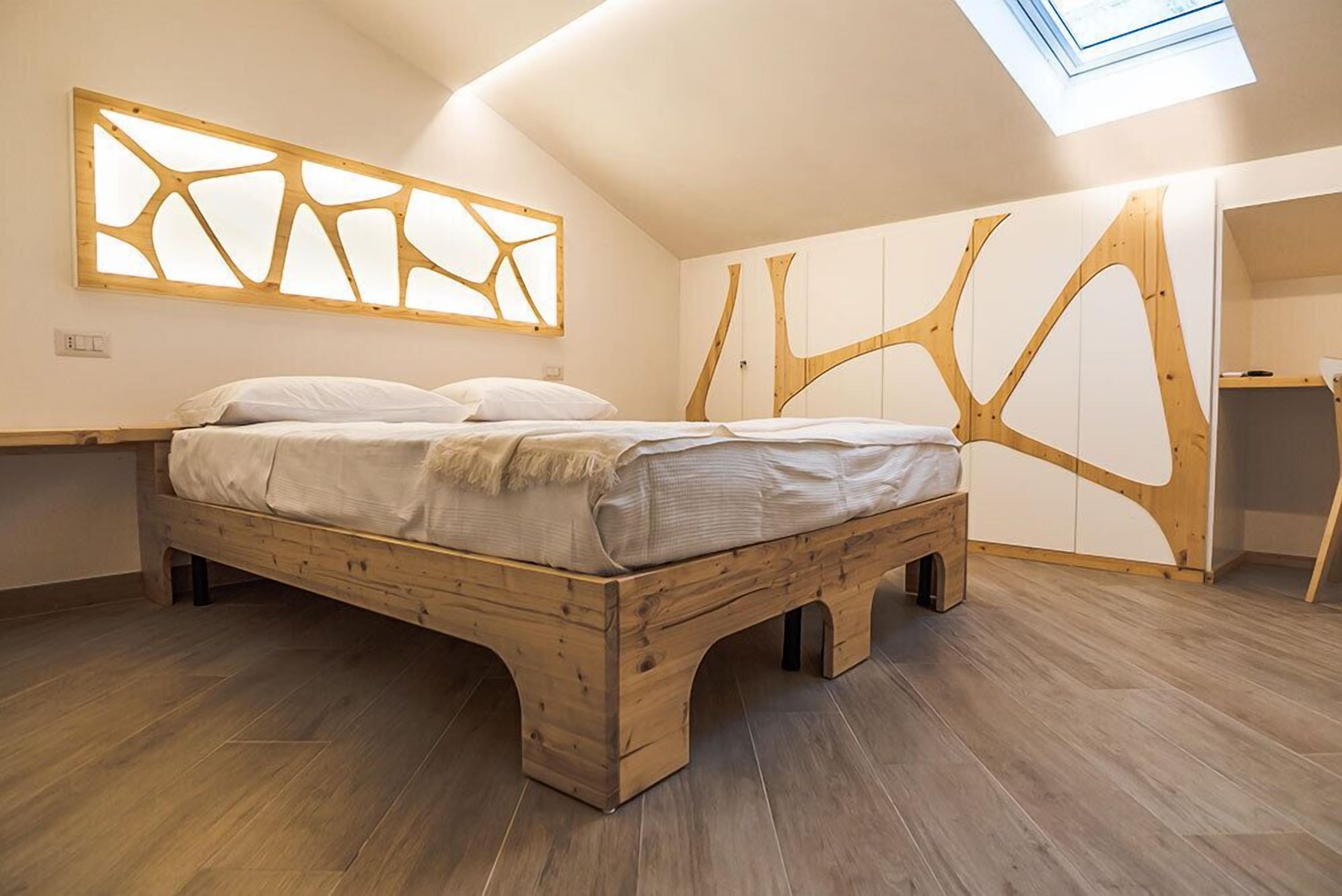 A bedroom with a wooden bed, a skylight, and a unique wall design.