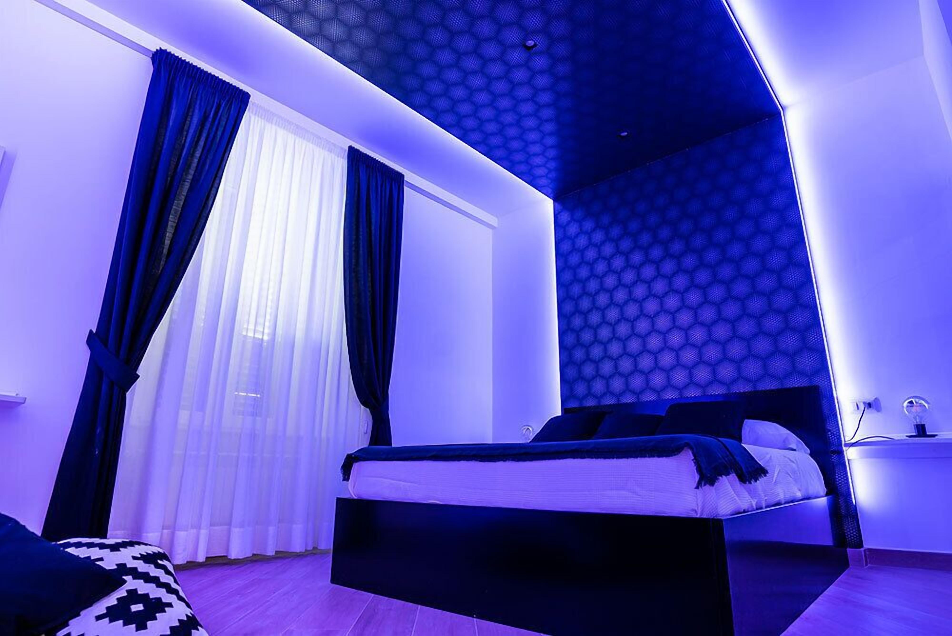 A modern bedroom with a bed, curtains, and a patterned wall.