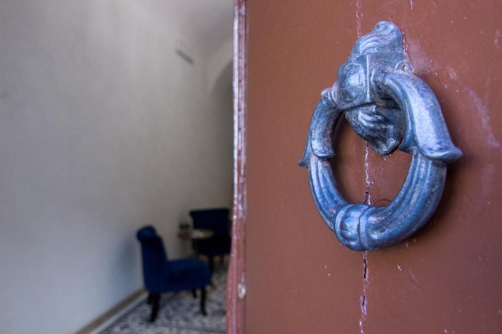 Una porta con maniglia ad anello in metallo e una crepa visibile nel telaio.