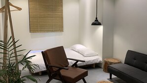 Un salon moderne avec un canapé, un fauteuil marron, une petite table ronde, une plante en pot et un grand panier tressé.