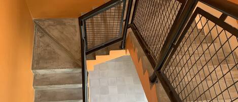 Una escalera con barandillas metálicas y un rellano con azulejos.