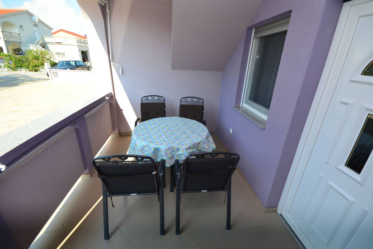 A balcony with a table and chairs, a window, and a door.