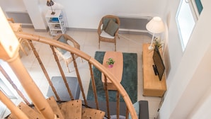 En spiraltrappa i en modern inredning med utsikt över ett vardagsrum, ett skrivbord och ett fönster.