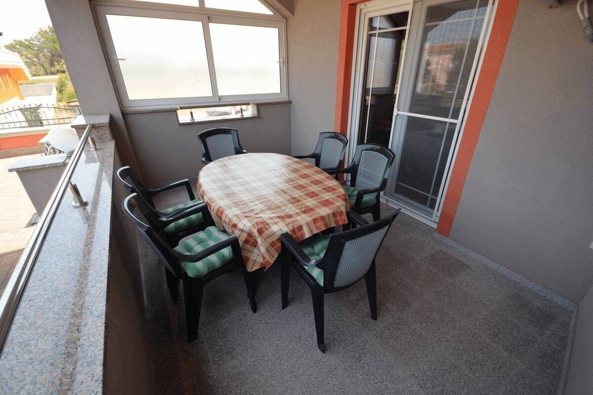 A balcony with a table and chairs, a window, and a door.
