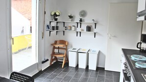 A compact kitchen with white shelves, a wooden chair, and a small table. - Pixie Home (Hanau)