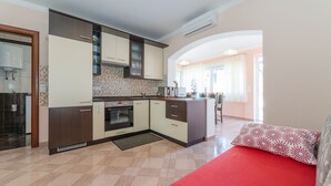 Una cocina moderna con una isla central, un comedor con sofá rojo y vistas al salón.