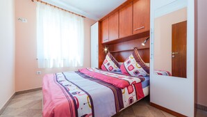 Un dormitorio con cama, armario de madera y ventana con cortinas.
