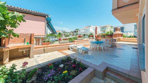 Una terraza en la azotea con mobiliario exterior, una fuente de agua y un jardín.