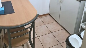 A compact kitchen with a dining table, a coffee maker, and a trash bin. - Mixie Home (Hanau)