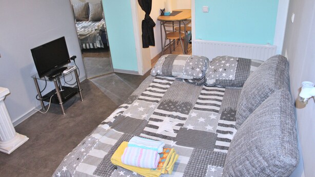 A cozy room with a bed, a TV, and a dining area. - Mixie Home (Hanau)