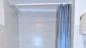 A bathroom with a bathtub, a shower curtain, a towel rack, and a sink with a mirror. - Mixie Home (Hanau)