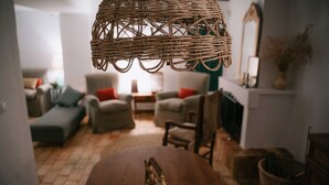 Een gezellige woonkamer met een wilgentakken kroonluchter, een houten tafel met een pompoen decoratie, en een open haard.
