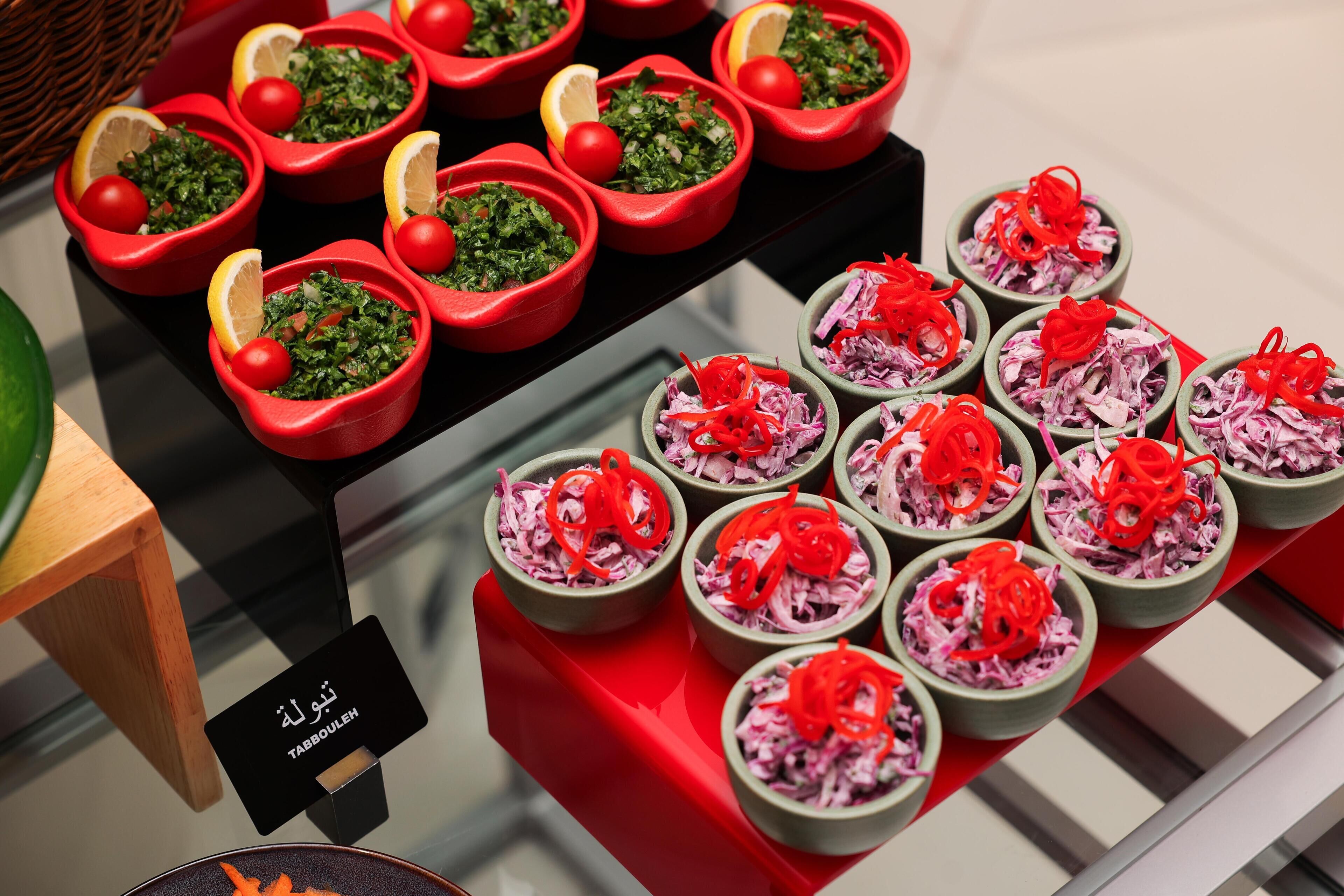 Variedad de alimentos en cuencos, algunos con aderezos rojos y verdes, dispuestos sobre una mesa.
