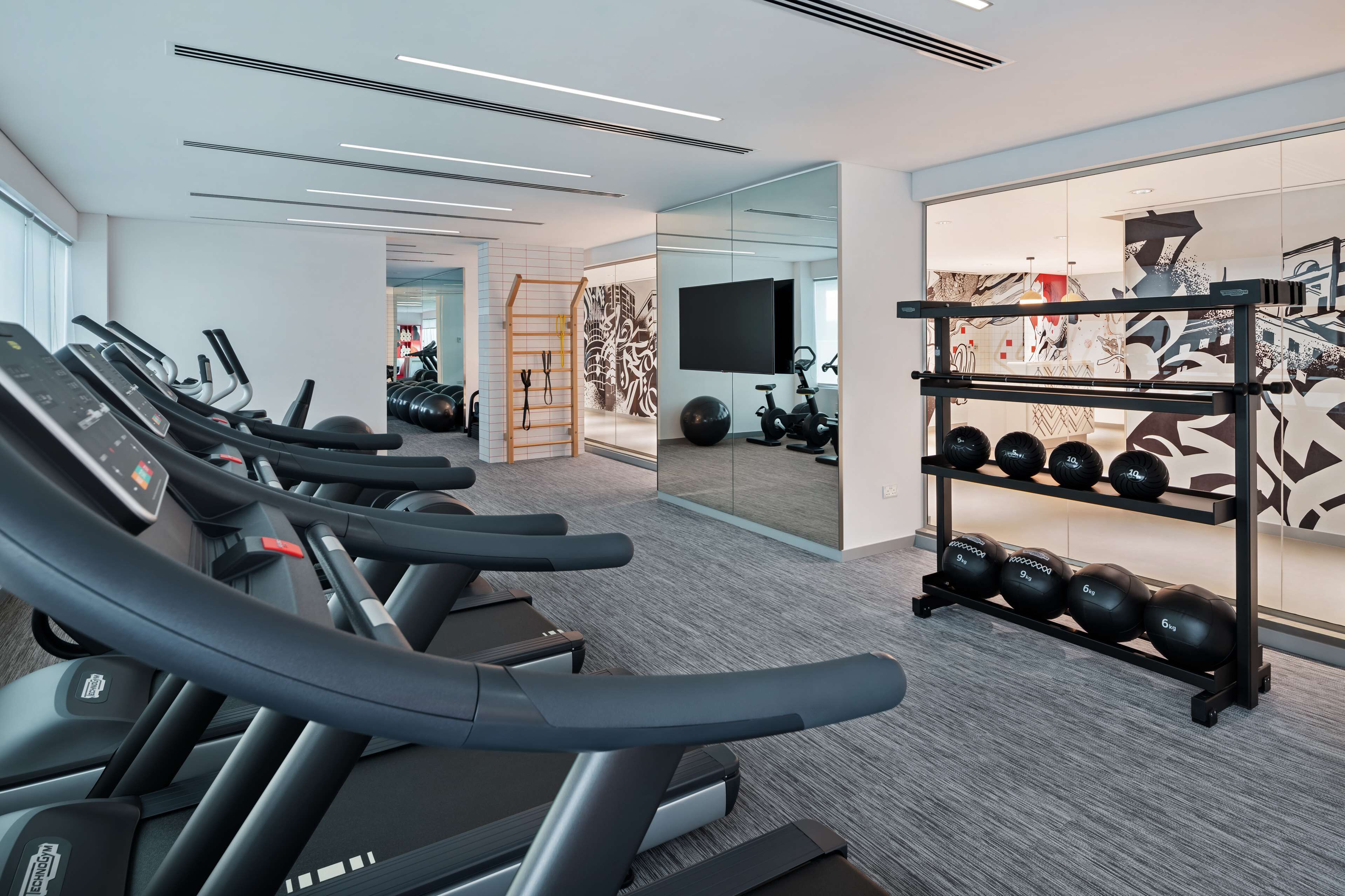 Ett modernt gym med löpband, en stång för vikter och en vägg med speglar.