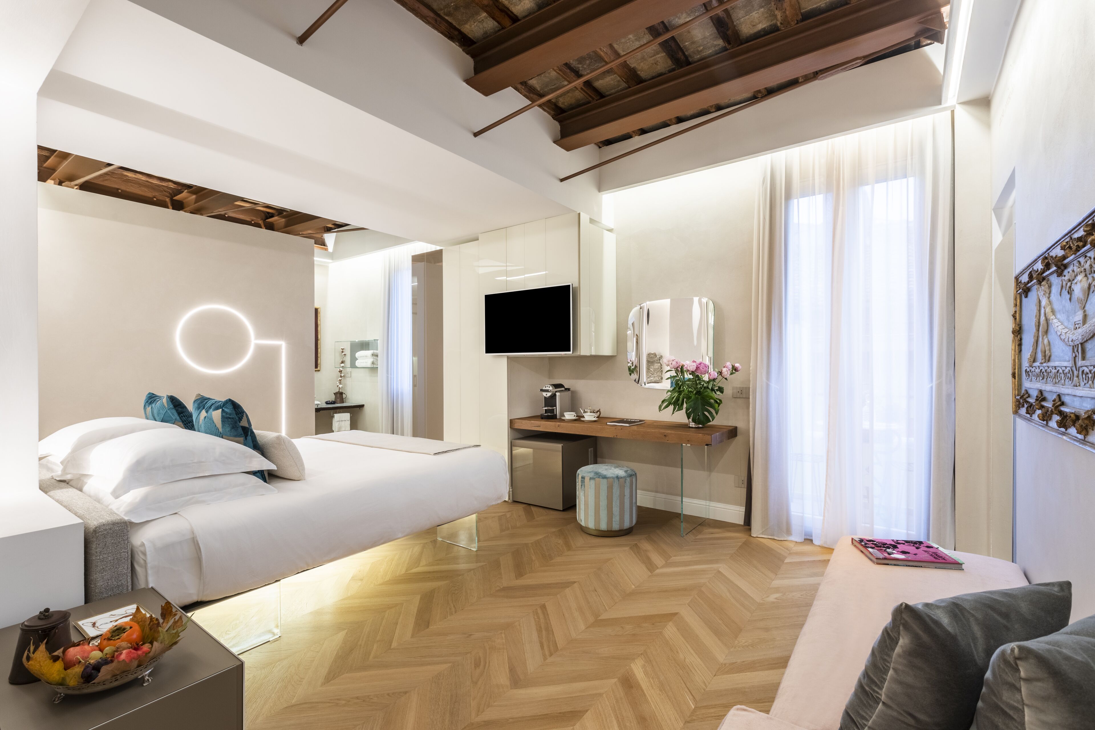 Una habitación de hotel moderna con una cama, un escritorio, un televisor y una kitchenette.