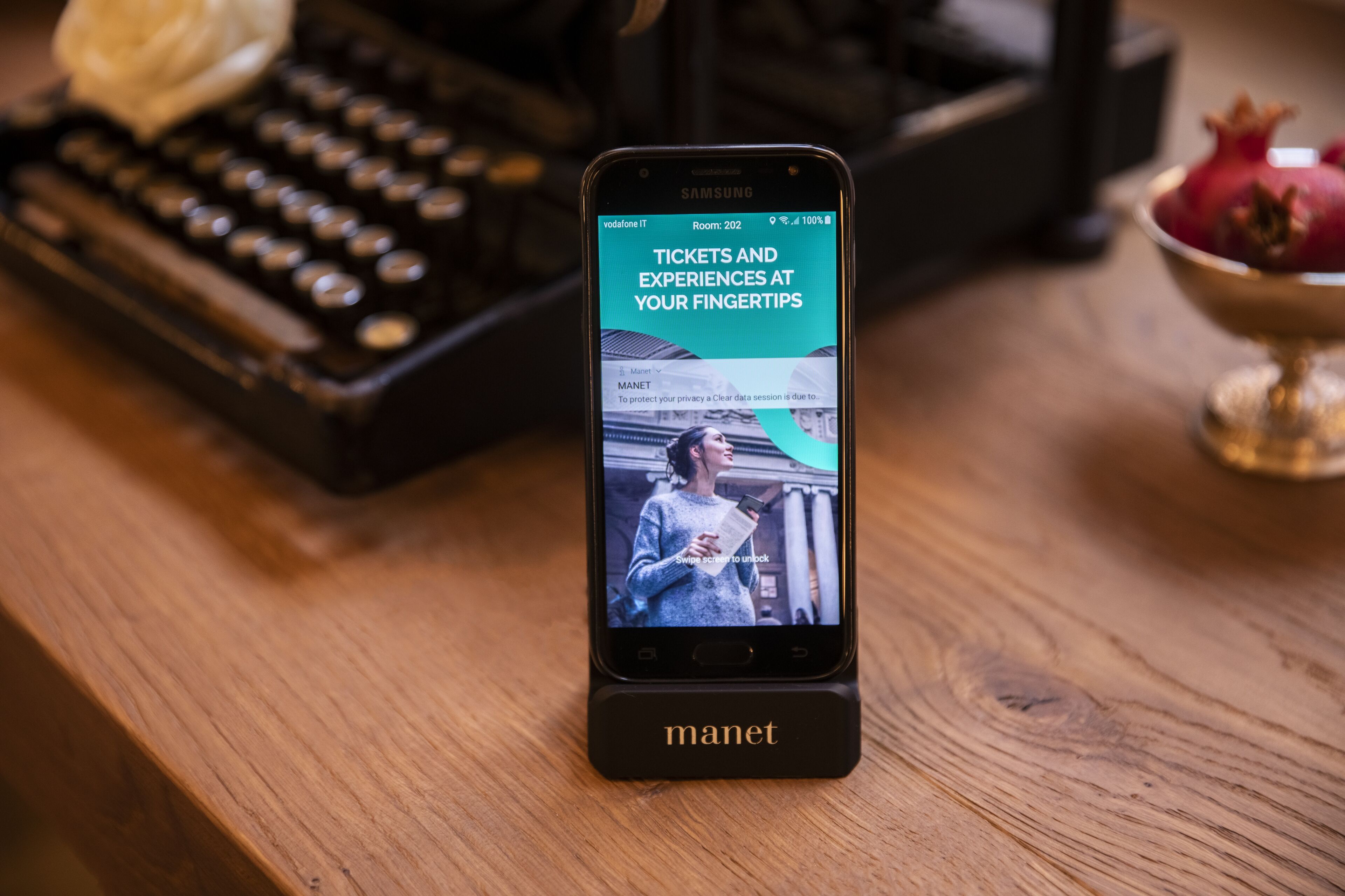 A smartphone on a wooden surface displaying a news article titled "Tickets and Experiences at Your Fingertips."