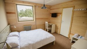 Un dormitorio con cama, escritorio, silla, televisor y armario.