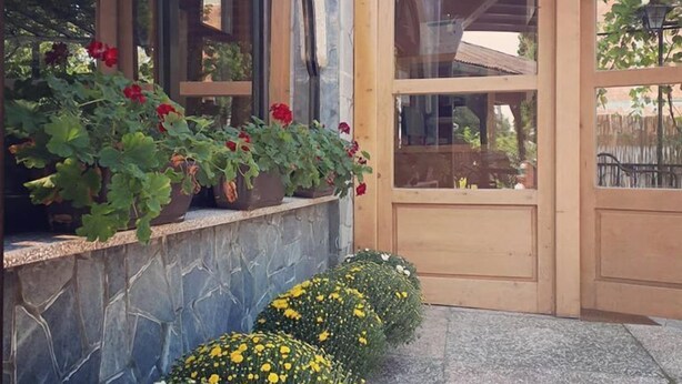 Un edificio con fachada de piedra, puertas de madera y un área de entrada cubierta.