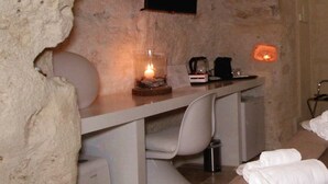 A stone-walled room with a bed, a desk, and a television mounted on the wall. - Il Casale di Maria (Matera)