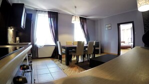 A modern dining area with a wooden table and chairs, a bench, and a ceiling light fixture. - Victus Apartamenty - Etna (Sopot)