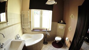 A bathroom with a bathtub, sink, toilet, and a window providing natural light. - Victus Apartamenty - Etna (Sopot)