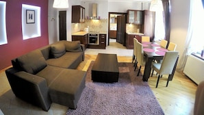 A modern living room with a sofa, a coffee table, and a dining area with a table and chairs. - Victus Apartamenty - Etna (Sopot)
