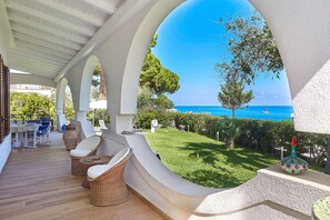 A covered outdoor area with wicker furniture, a view of the sea, and a well-maintained lawn. - Villa with direct sea access near Palermo (Carini)