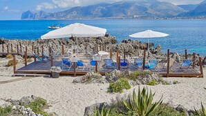 A beach with sun loungers, umbrellas, and a rocky shoreline. - Villa with direct sea access near Palermo (Carini)
