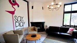 A living room with a sofa, armchair, and coffee table. There is a fireplace and a chandelier. - Victus Apartamenty - Flamingo (Sopot)