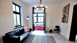 A modern living room with a black leather sofa, a striped rug, and a dining area in the background. - Victus Apartamenty - Flamingo (Sopot)