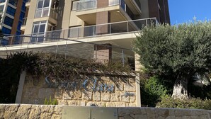 A tall residential building with multiple balconies and a stone wall with a sign. - Mediterranean Santa Clara 4A (Calpe)