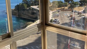 A view from a high-rise window overlooking a coastal area with a parking lot and a road with vehicles. - Mediterranean Santa Clara 4A (Calpe)
