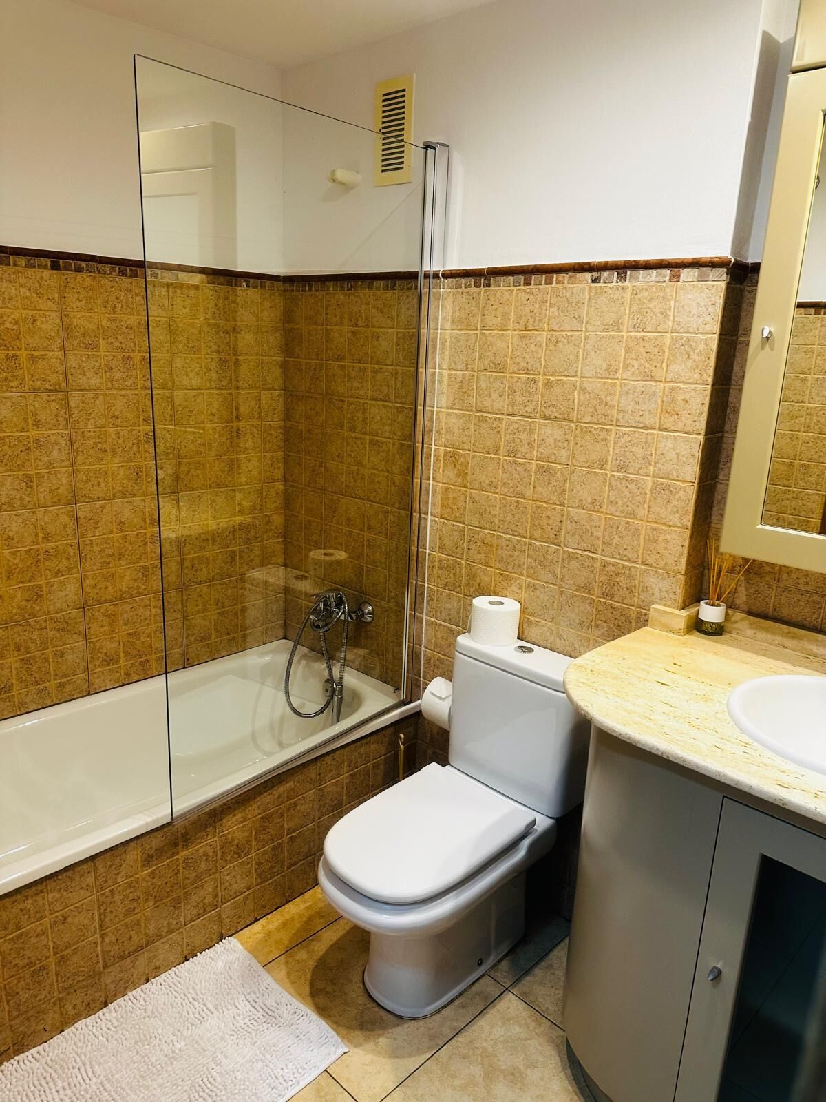A bathroom with a glass-enclosed shower, a toilet, and a sink.