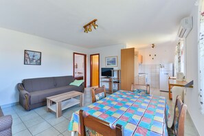 Ein gemütlicher Wohnraum mit einer Couch, einem Holztisch und einer farbenfrohen, gesteppten Tischdecke.