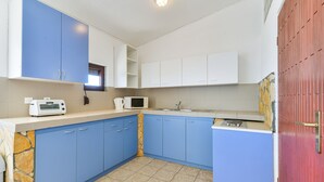 Una cocina con armarios azules, una pared de acento de piedra, un microondas y un tostador.