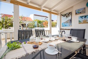 Zona de menjador a l'aire lliure amb taula preparada per a dues persones, incloent una tassa de cafè, teiera i plats.