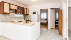 A compact kitchen with a built-in island, wooden cabinets, and a microwave. - Apartment Poslon (Vir)