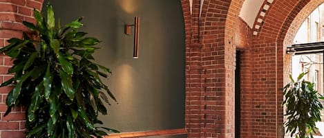 A modern interior with brick arches, a blue sofa, a yellow armchair, and a large potted plant.
